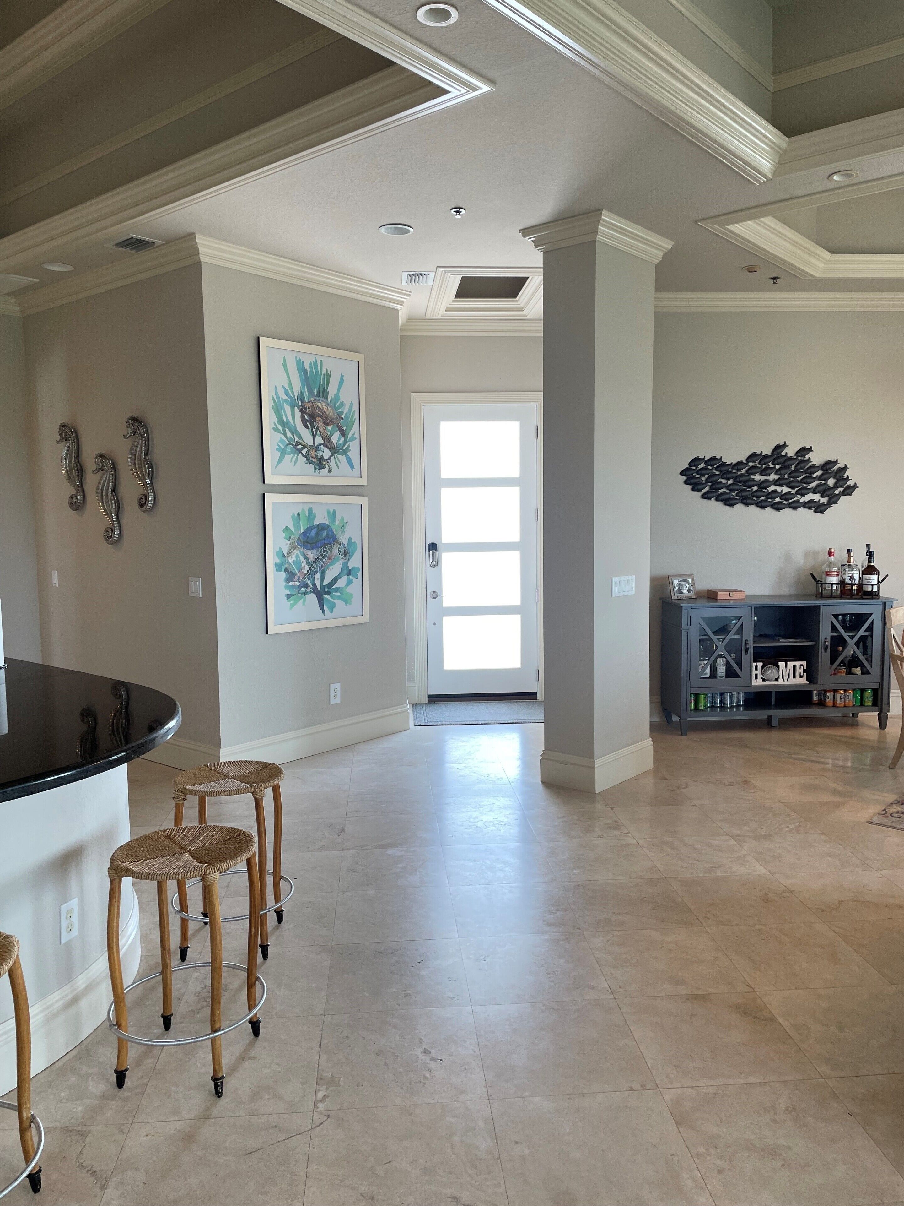 A spacious kitchen with a curved island, bar stools, and a cabinet with a 'HOME' sign.