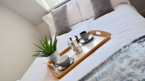 A neatly made bed with a tray holding a small potted plant, a cup, and a teapot. - Beautiful 3-bed House in Wolverhampton (Wolverhampton)