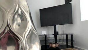 A modern living room with a marble coffee table, a flat-screen TV on a black stand, and a decorative glass vase. - Beautiful 3-bed House in Wolverhampton (Wolverhampton)