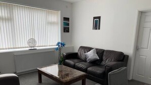 A living room with a leather sofa, a coffee table, and a chair. - Beautiful 3-bed House in Wolverhampton (Wolverhampton)