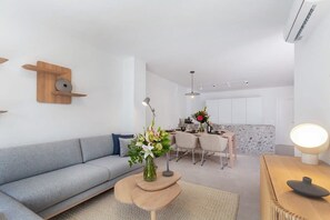 A modern living room with a sofa, a coffee table, and a dining area with chairs and a table.