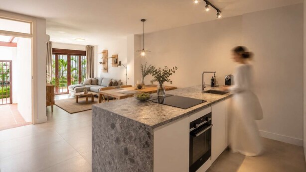 A modern kitchen with a large island, built-in oven, and pendant lighting.