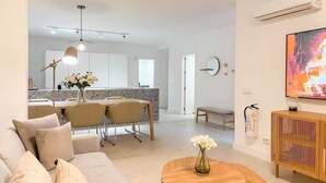A modern living room with a sofa, coffee table, and a dining area with chairs and a table.