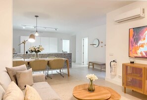 A modern living room with a sofa, coffee table, and a dining area with chairs and a table. - La Maestranza | Puerto Banus Townhouse Bbq Pool (Marbella)