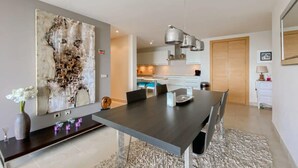 A modern dining area with a dark wooden table, chairs, and a large abstract painting on the wall. - Samara 2 | Marbella Luxury Spa Gym Pools Views (Marbella)