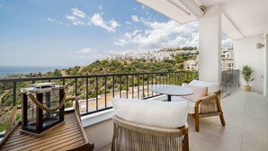 A balcony with a view of a coastal town, a table, and wicker chairs. - Samara 2 | Marbella Luxury Spa Gym Pools Views (Marbella)