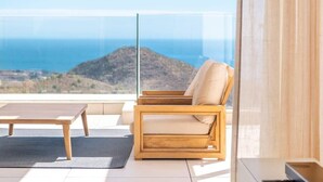 A balcony with a view of the sea and hills, a wooden chair, and a small table. - Palo Alto | Marbella Luxury Rooftop Penthouse (Ojén)