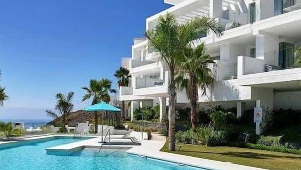 A modern hotel with a pool, white exterior, and palm trees. - Palo Alto | Marbella Luxury Rooftop Penthouse (Ojén)