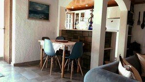 Et spiseområde med bord og stole, et køkken med komfur og skabe, og en opholdsstue med sofa.