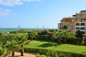 Guests can enjoy a scenic view of the sea from the hotel's Mediterranean-style building, surrounded by a well-maintained garden with palm trees and manicured lawns.