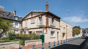 Un edificio de dos pisos con fachada de ladrillo, contraventanas blancas y una chimenea.
