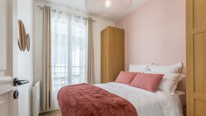 A bedroom with a bed, curtains, a wooden wardrobe, and a radiator.