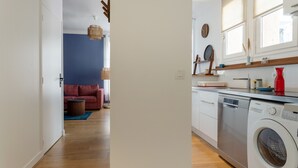 A modern kitchen with a dishwasher and a red vase on the counter.