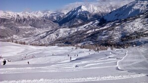 Un paysage montagneux enneigé, avec des pistes de ski et un ciel dégagé.