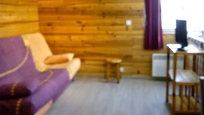 Une pièce avec un mur en bois, un canapé violet, une petite table et une chaise.