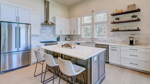 A modern kitchen with white cabinetry, stainless steel appliances, and a large island with bar stools. - New/Modern Rustic/Mins. to Blue Ridge/Spacious/Hot Tub (Mineral Bluff)