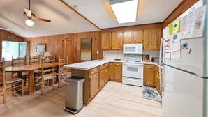 A kitchen with wooden cabinets, a microwave, a stove, and a refrigerator. - Longs for the Sea - North Litchfield Beach (Pawleys Island)