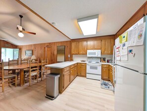 A kitchen with wooden cabinets, a microwave, a stove, and a refrigerator. - Longs for the Sea - North Litchfield Beach (Pawleys Island)
