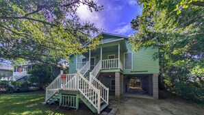 A two-story house with a front porch, a staircase, and a sign indicating beach vacation rentals. - Longs for the Sea - North Litchfield Beach (Pawleys Island)
