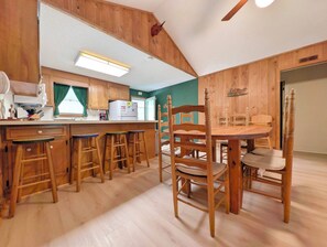 A kitchen with wooden cabinets, a dining table with chairs, and a bar area with stools.