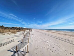 A beach with a wooden fence, sandy beach, and ocean.