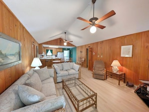 Une pièce chaleureuse avec un plafond en bois, un ventilateur de plafond, un coin repas avec une table et des chaises, et un canapé.