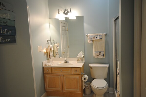 A bathroom with a wooden vanity, a sink, a mirror, a toilet, and a shower area.