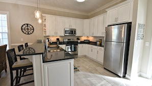 Una cocina moderna con armarios blancos, electrodomésticos de acero inoxidable y una isla central.