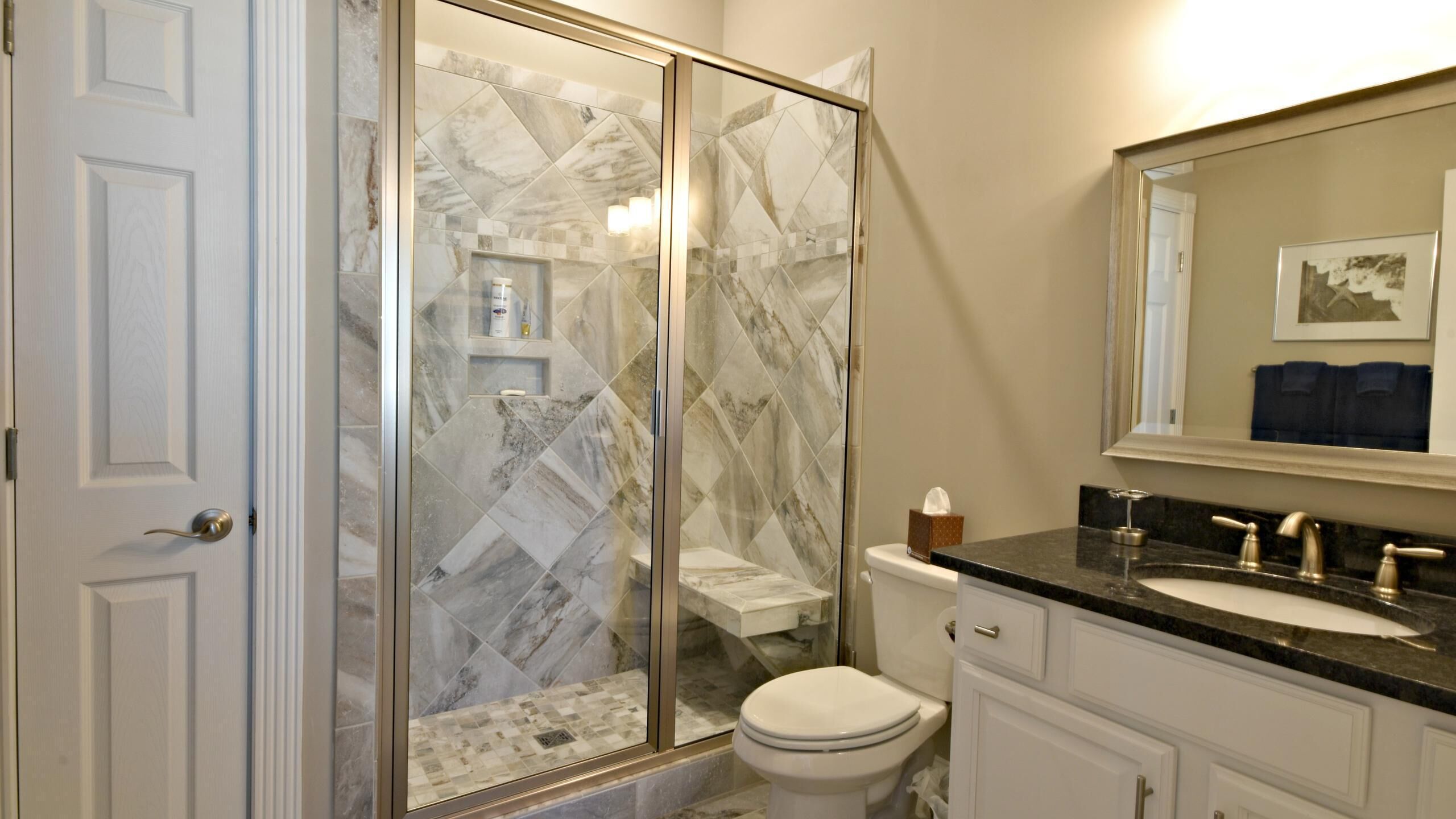 Une salle de bain avec une douche à parois de verre, des toilettes, un lavabo et un meuble-lavabo avec des placards.