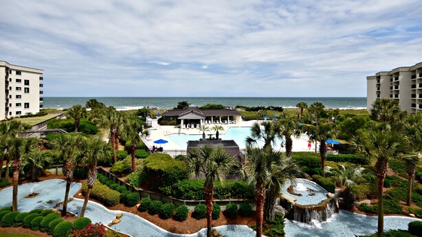 Un resort con piscina, palmeras y vista al océano.