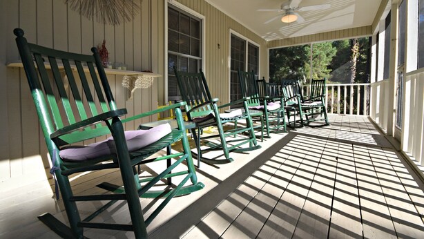 A covered porch with wooden flooring and green rocking chairs. - Our Favorite Perch Second Row - North Litchfield Beach (Pawleys Island)