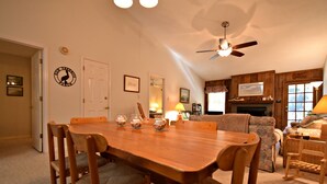 A dining area with a wooden table and chairs, a ceiling fan, and a fireplace. - Our Favorite Perch Second Row - North Litchfield Beach (Pawleys Island)