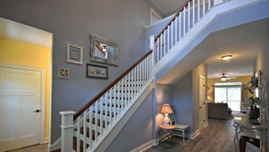 Un escalier avec des rampes blanches et des marches en bois menant à l’étage supérieur.