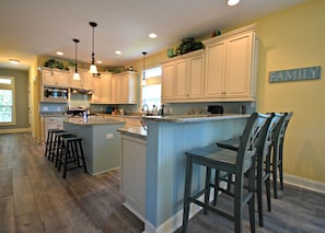 A spacious kitchen with a central island, bar stools, and a 'FAMILY' sign on the wall.