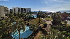 Een resort met een zwembad, palmbomen en uitzicht op de oceaan.