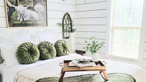 Une chambre à coucher avec un lit, un ventilateur de plafond, une fenêtre et une lampe fixée au mur.