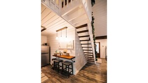 Une cuisine avec un îlot central en bois, des tabourets de bar et des luminaires suspendus.