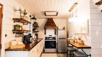 Una cocina estrecha con suelo de madera, armarios blancos y una isla central.