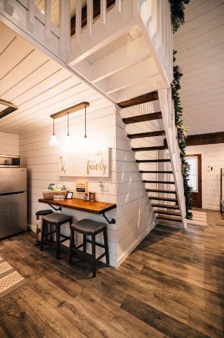 Cocina con isla de madera, taburetes de bar e iluminación colgante.