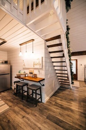 Een keuken met een houten kookeiland, barstoelen en hanglampen.