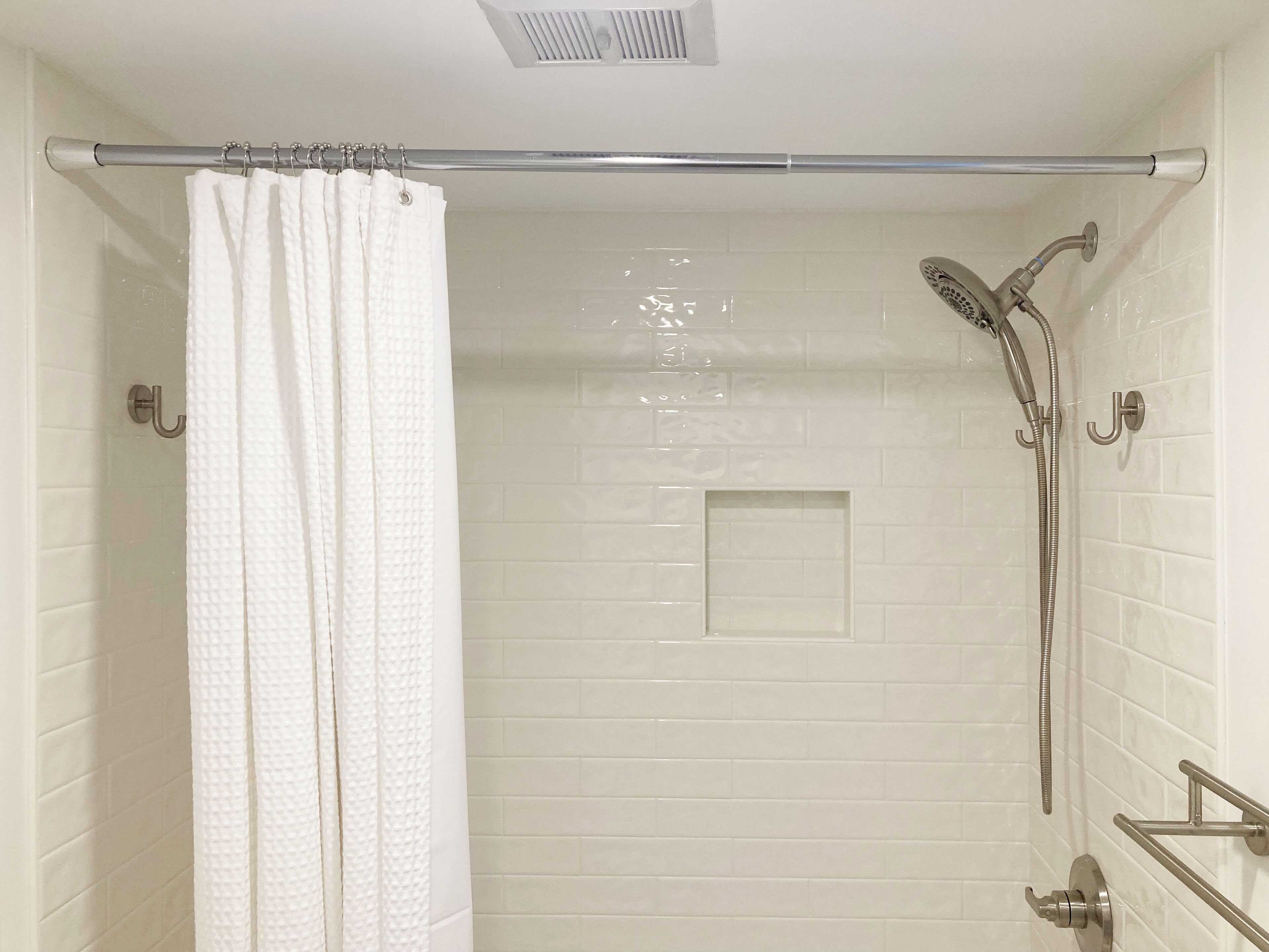 A shower with a handheld showerhead and a glass-enclosed shower area.