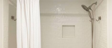 A shower with a handheld showerhead and a glass-enclosed shower area.