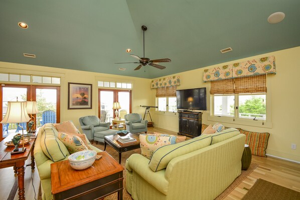 A living room with a sofa, armchairs, a television, and a ceiling fan. - Ocean View - North Litchfield Beach - Private Pool (Pawleys Island)