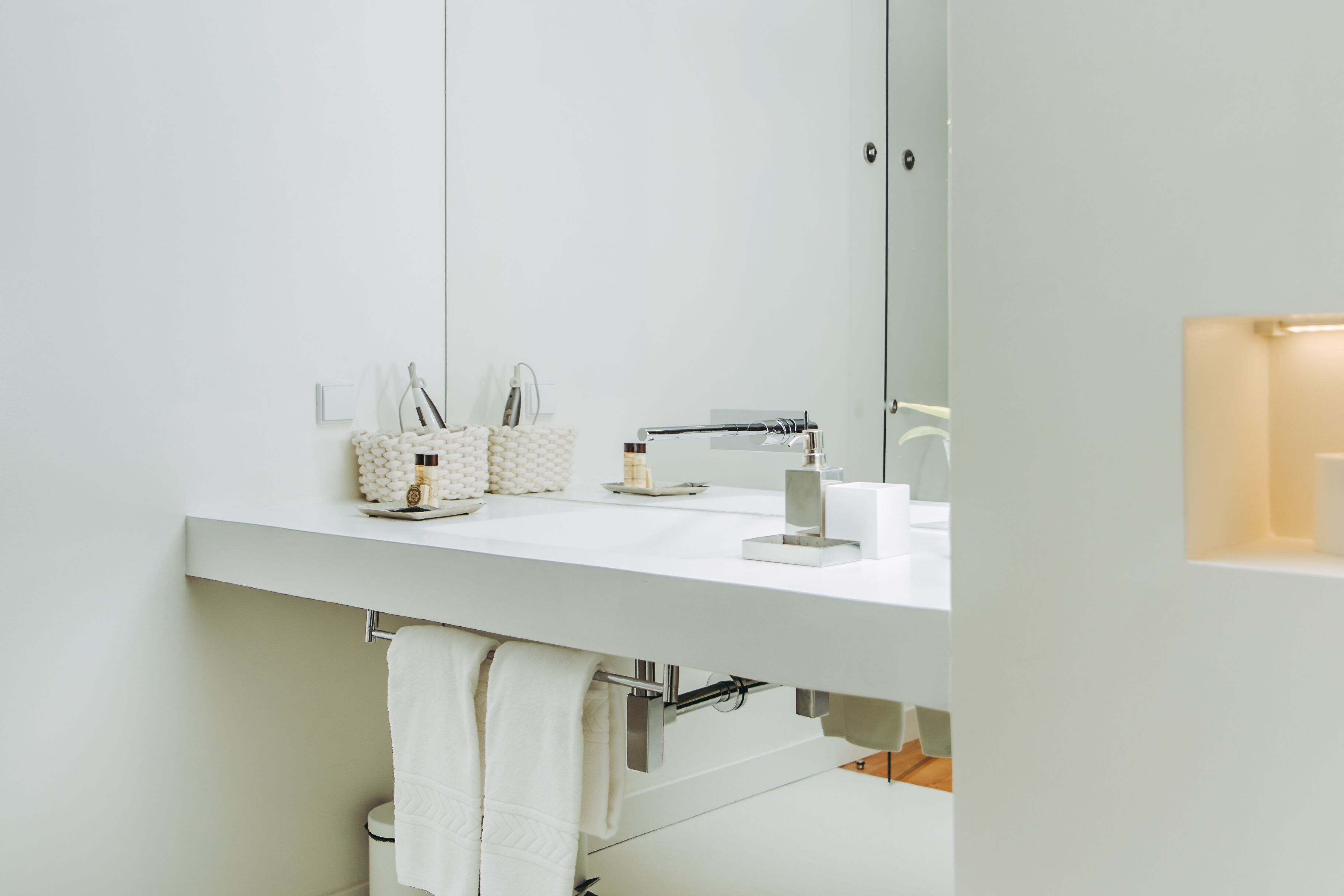 Une salle de bain moderne avec un lavabo blanc, un miroir et un porte-serviettes.