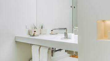 Une salle de bain moderne avec un lavabo blanc, un miroir et un porte-serviettes.