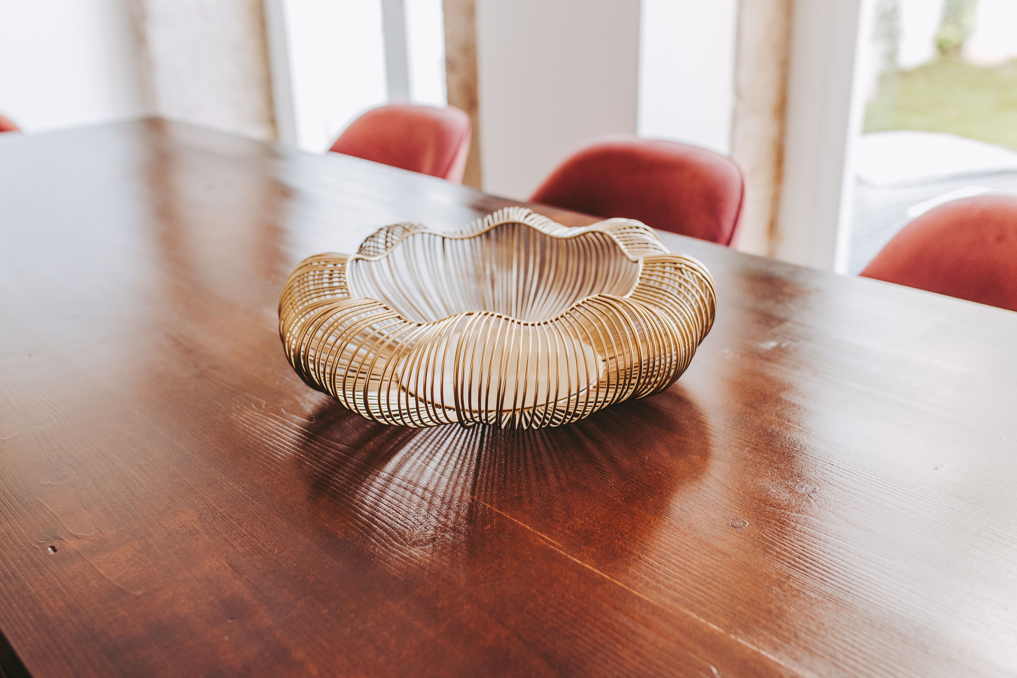 A wooden table with a woven bowl on it.