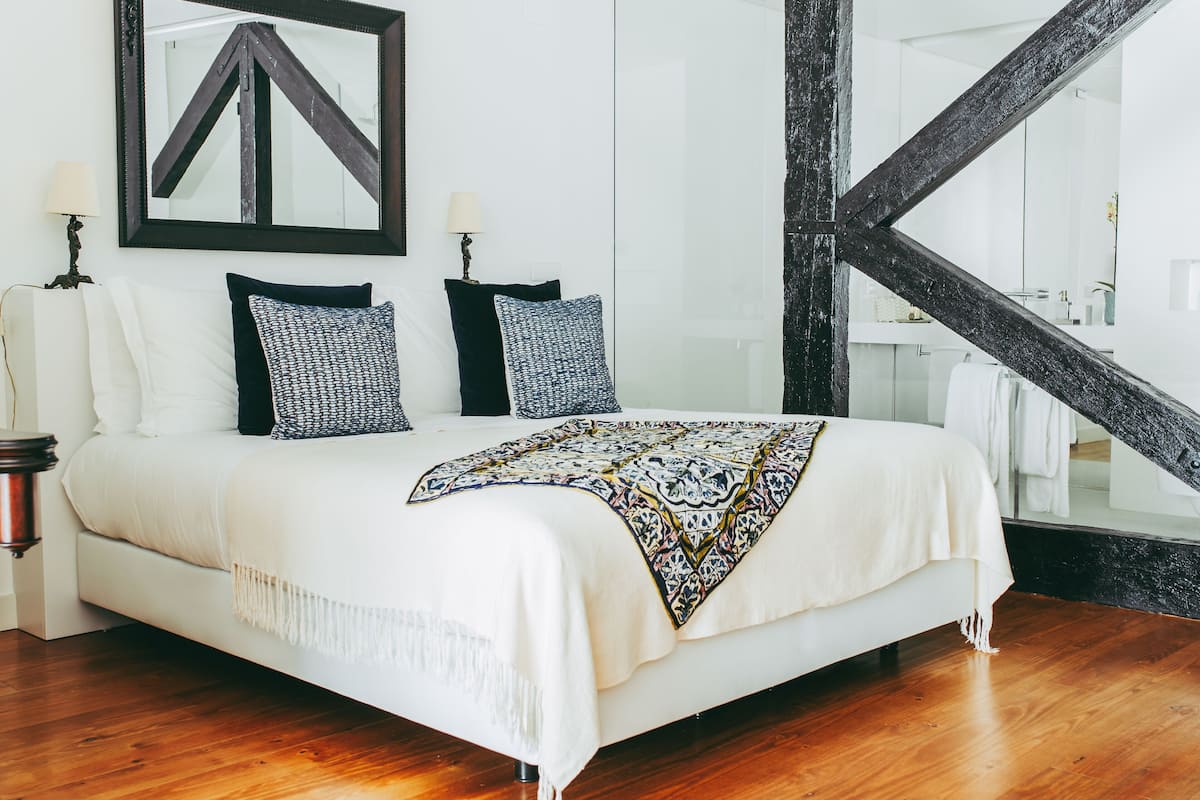 A modern bedroom with a large bed, a mirror, and a view of a bathroom.