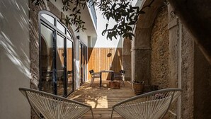 A cozy patio with two metal chairs, a wooden table, and a hanging plant. - 54 São Paulo – Exclusive Apartment Hotel (Lisbon)