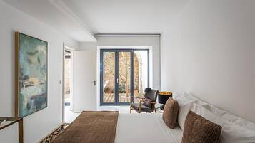 Una camera da letto con un letto grande, una sedia, una lampada e vista su uno spazio esterno tramite una porta scorrevole.