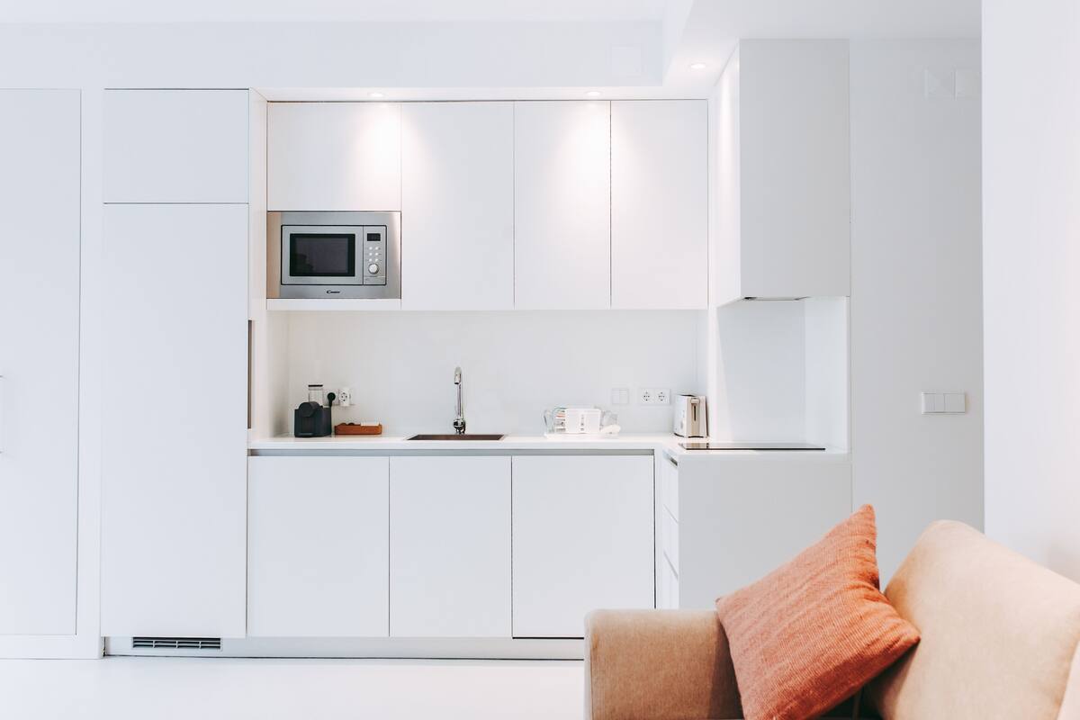 A modern kitchen with white cabinetry, a built-in microwave, and a sink.